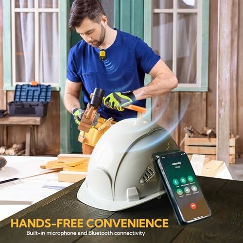 Man working with tools, hard hat with Bluetooth and microphone, smartphone nearby.