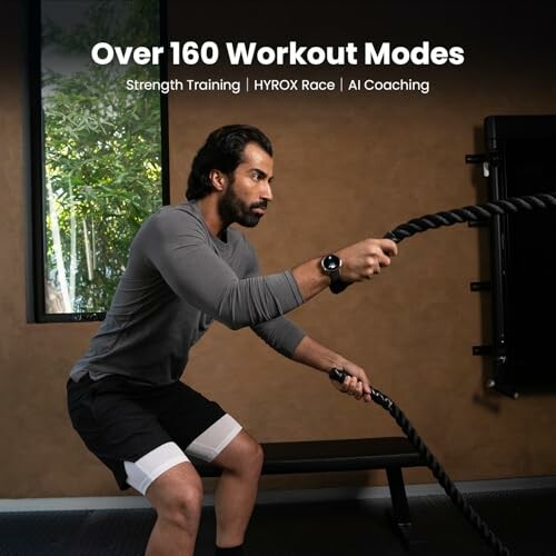 Man exercising with battle ropes in a gym.