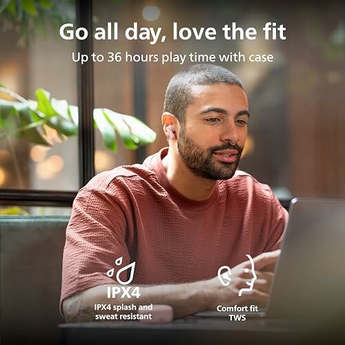 Man wearing earbuds using a laptop indoors