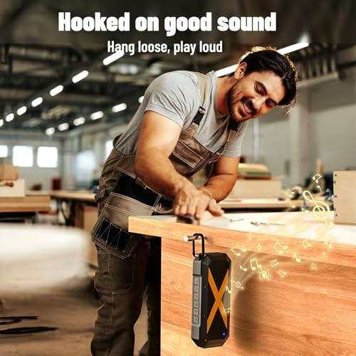 Man in workshop using a sanding tool, with a portable speaker playing music