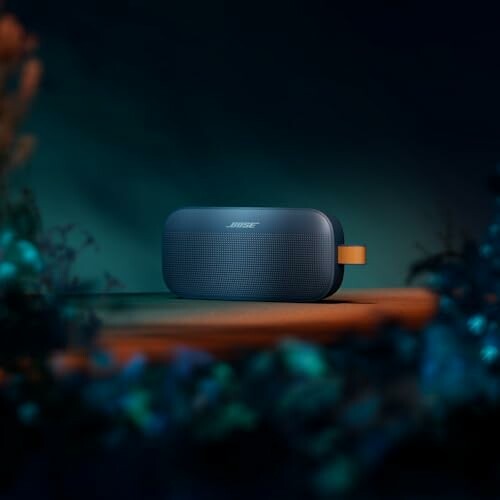 Portable Bluetooth speaker on a table with a dark background.